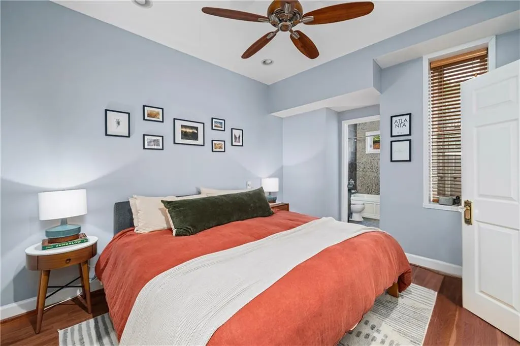Bedroom with wood finished floors, ensuite bathroom, and a ceiling fan