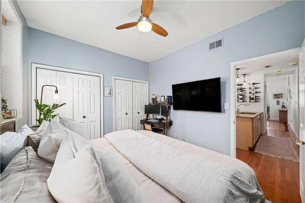 Bedroom with dark wood finished floors, multiple closets, and a ceiling fan