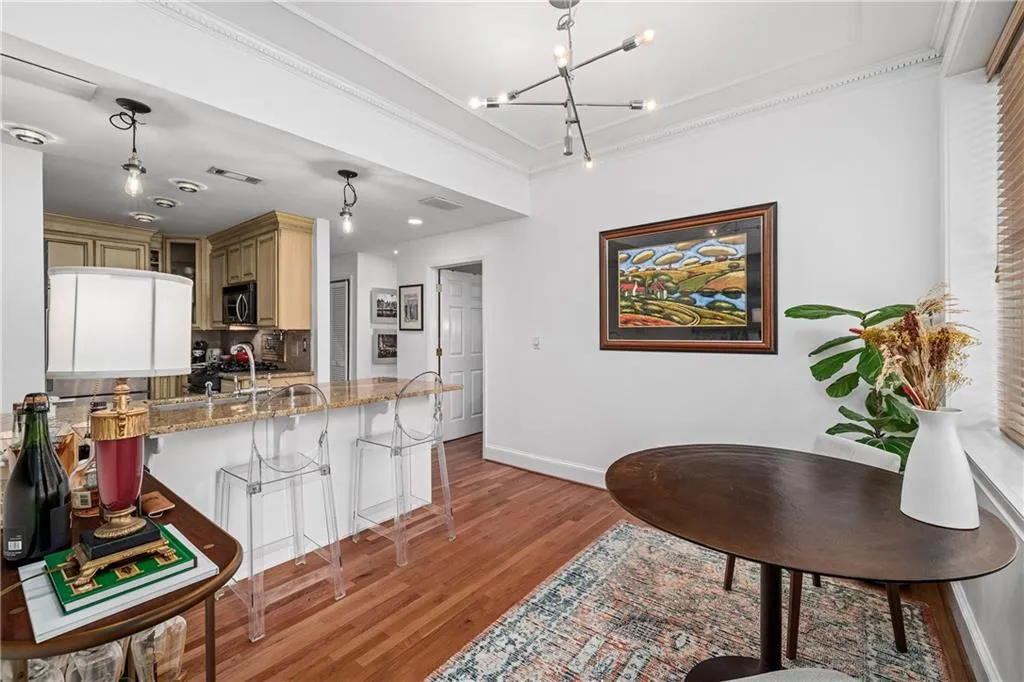 Kitchen featuring a kitchen bar, light stone counters, ornamental molding, pendant lighting, and light wood-type flooring