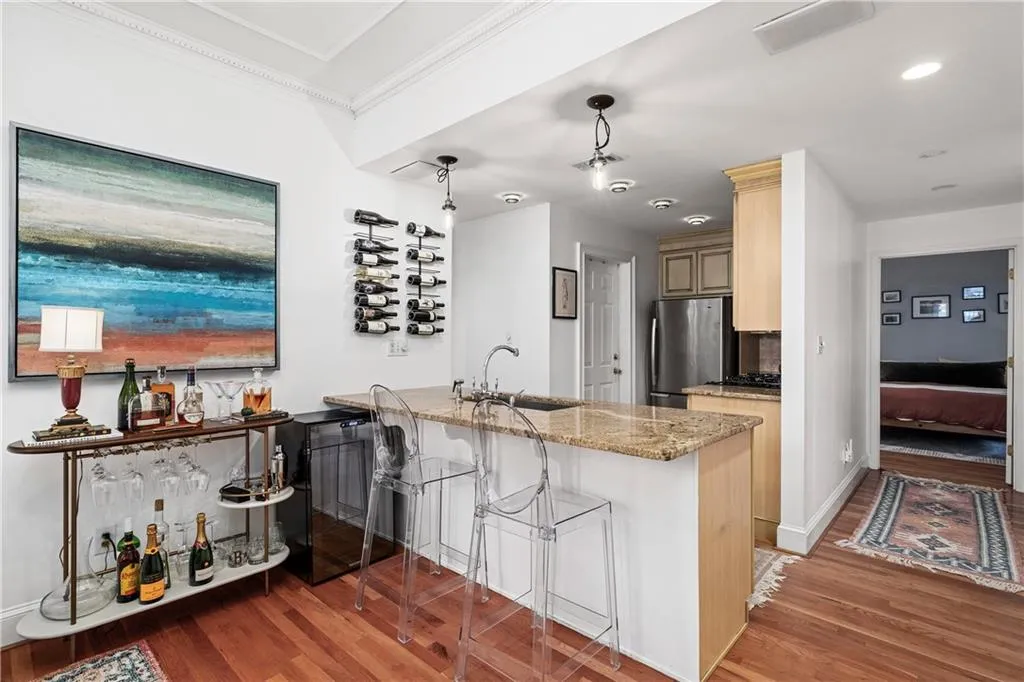 Kitchen featuring a peninsula, light brown cabinetry, light stone countertops, light wood-style flooring, and a kitchen breakfast bar