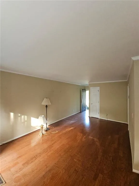Unfurnished room with wood finished floors and ornamental molding