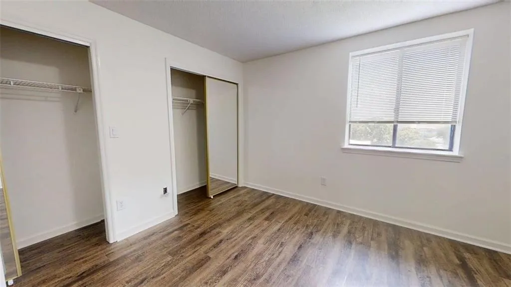 Unfurnished bedroom with dark wood-style floors and multiple closets