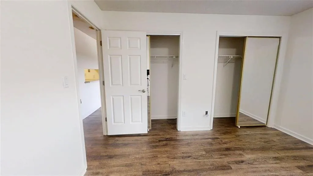 Unfurnished bedroom with multiple closets and dark wood finished floors