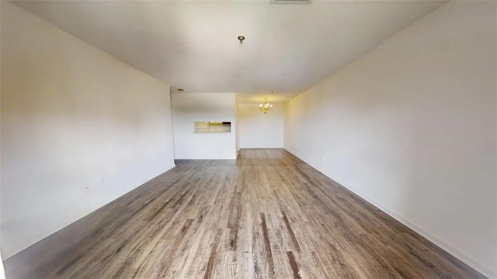 Unfurnished living room featuring wood finished floors and a chandelier