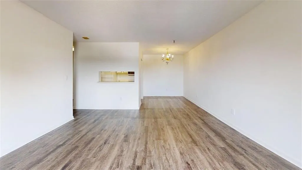 Unfurnished room featuring wood finished floors and a chandelier