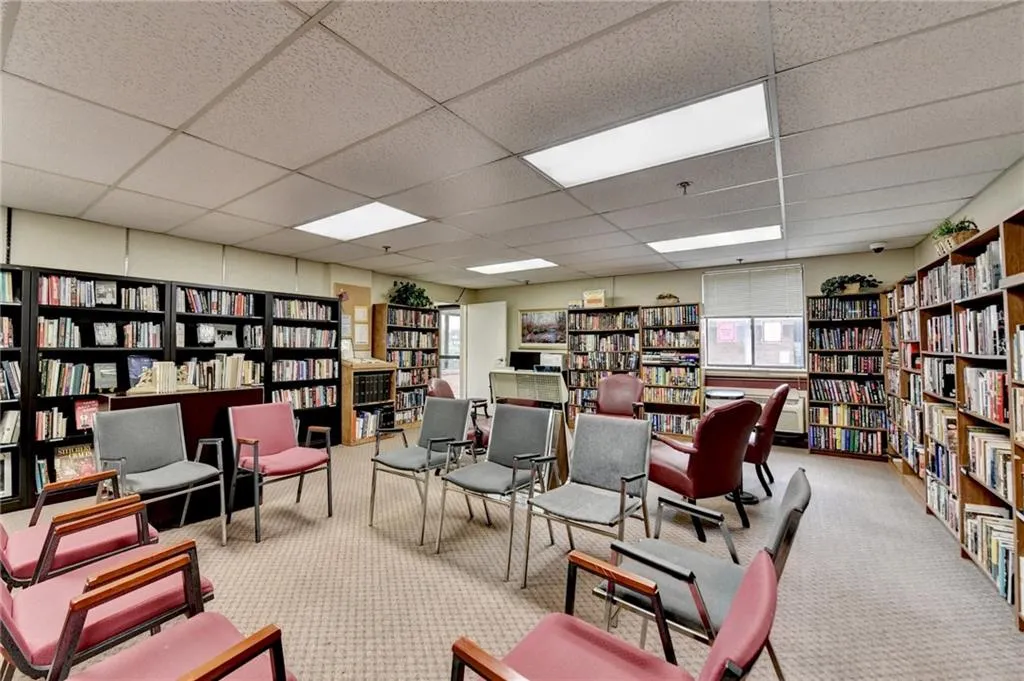 Sitting room featuring wall of books, plenty of natural light, and a drop ceiling