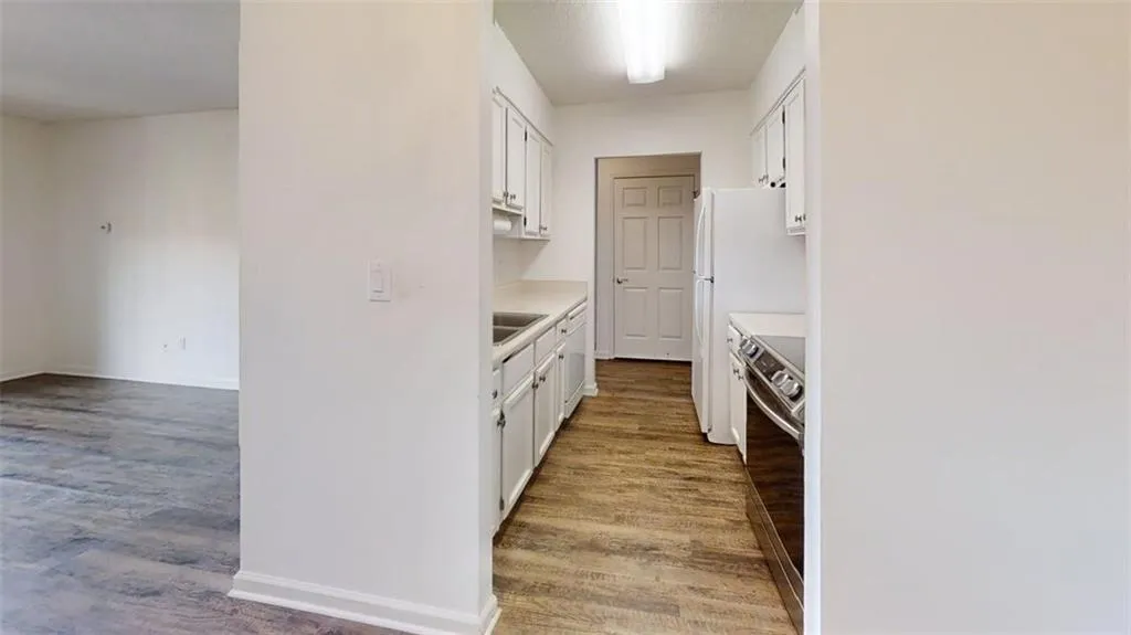 Kitchen featuring light countertops, white cabinets, stainless steel stove, and light wood-style floors