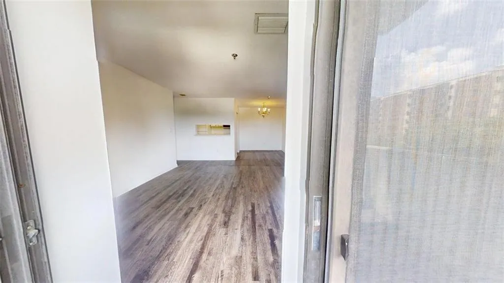 Corridor featuring wood finished floors and a chandelier