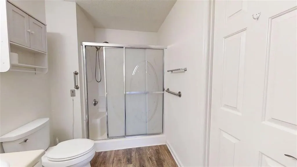 Full bath featuring a shower stall, dark wood-type flooring, and vanity