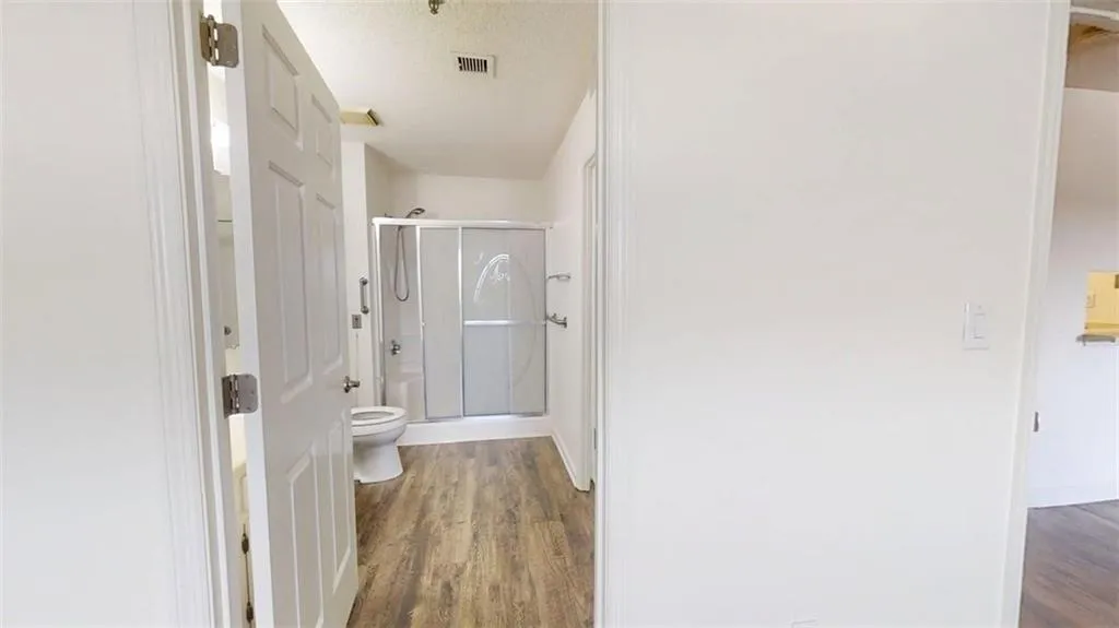 Full bathroom featuring dark wood-style flooring and a stall shower