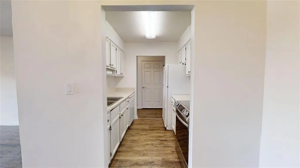 Kitchen featuring light countertops, white cabinetry, electric range, and dark wood-style floors