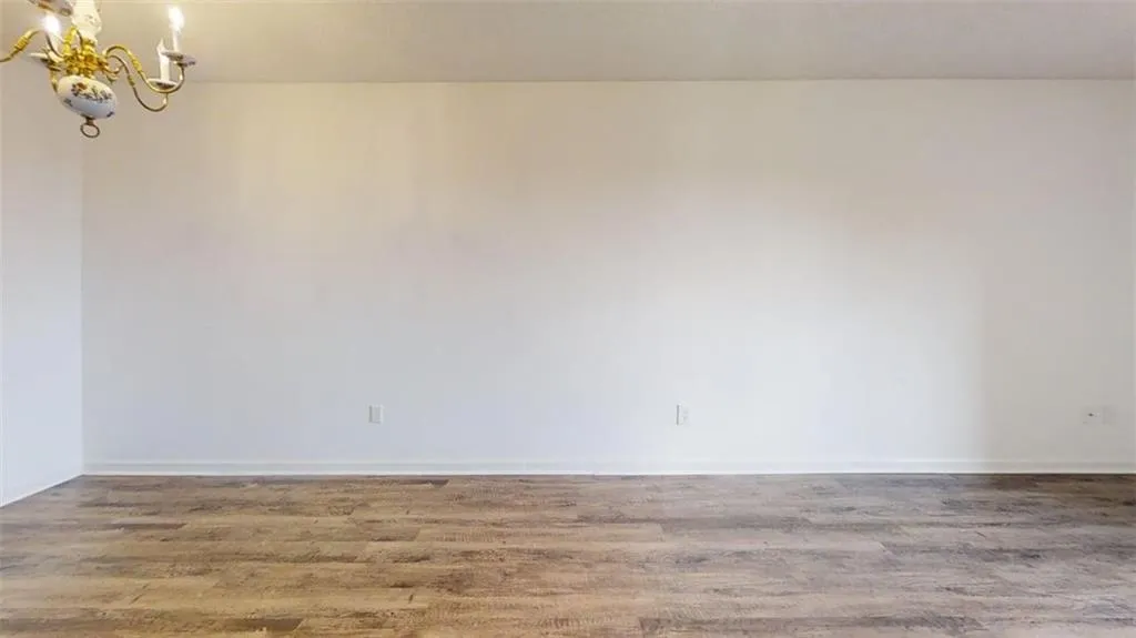 Empty room with wood finished floors and a chandelier