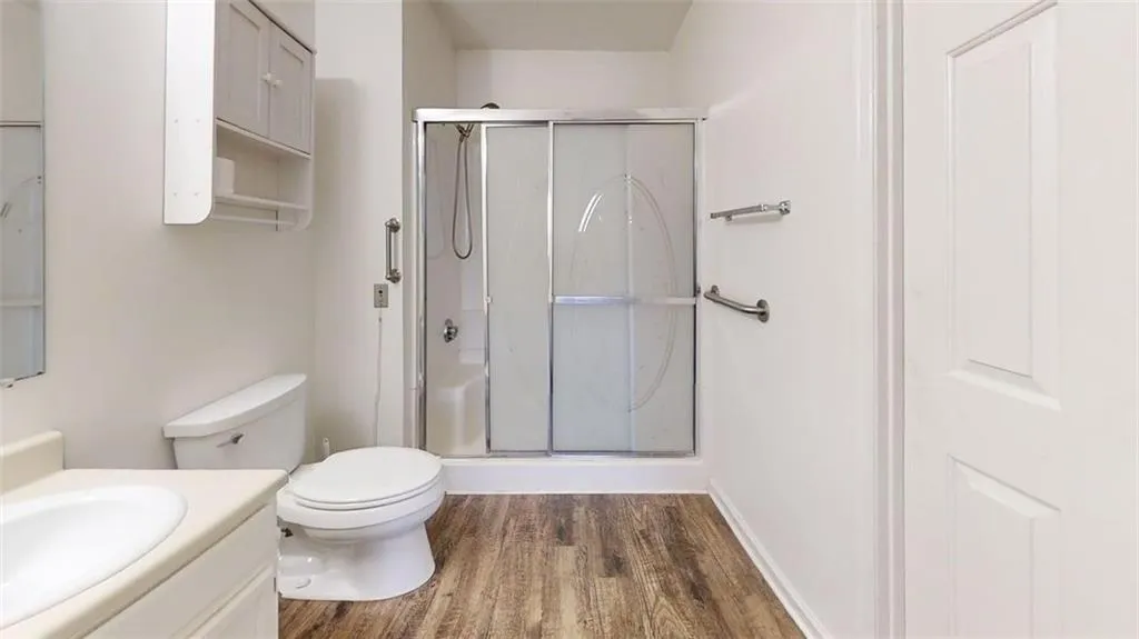 Bathroom with vanity, dark wood-style flooring, and a shower stall