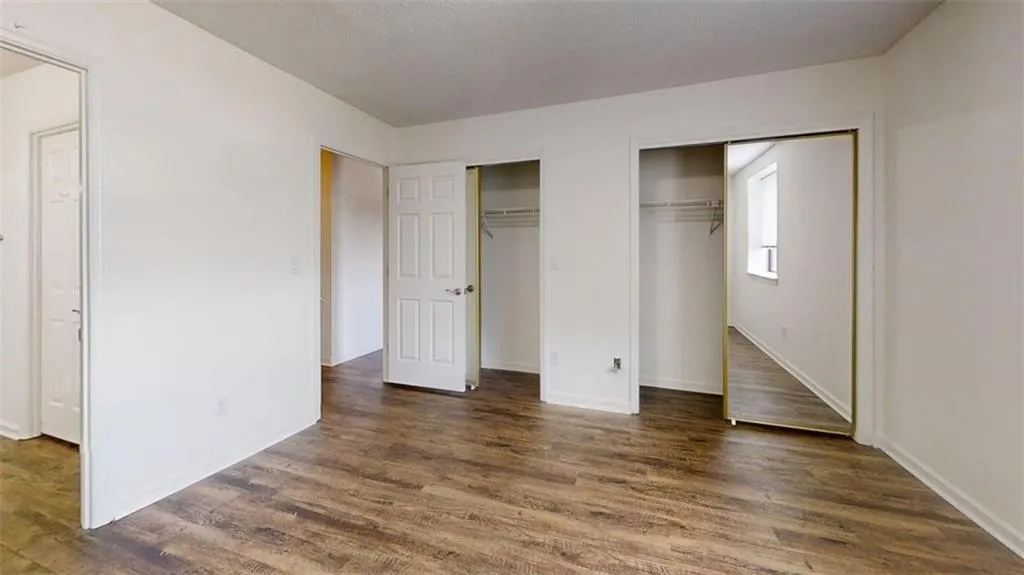 Unfurnished bedroom with multiple closets and dark wood finished floors