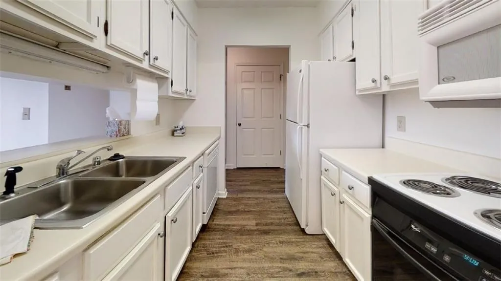 Kitchen featuring white appliances, light countertops, dark wood-type flooring, and white cabinetry