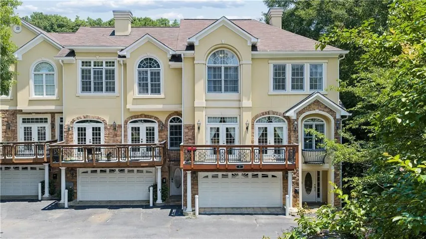 Multi-level stucco and stone exterior featuring multiple balconies, arched windows, and integrated garages
