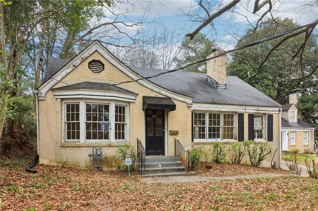 Bungalow-style house with entry steps, a shingled roof, a chimney, and brick siding