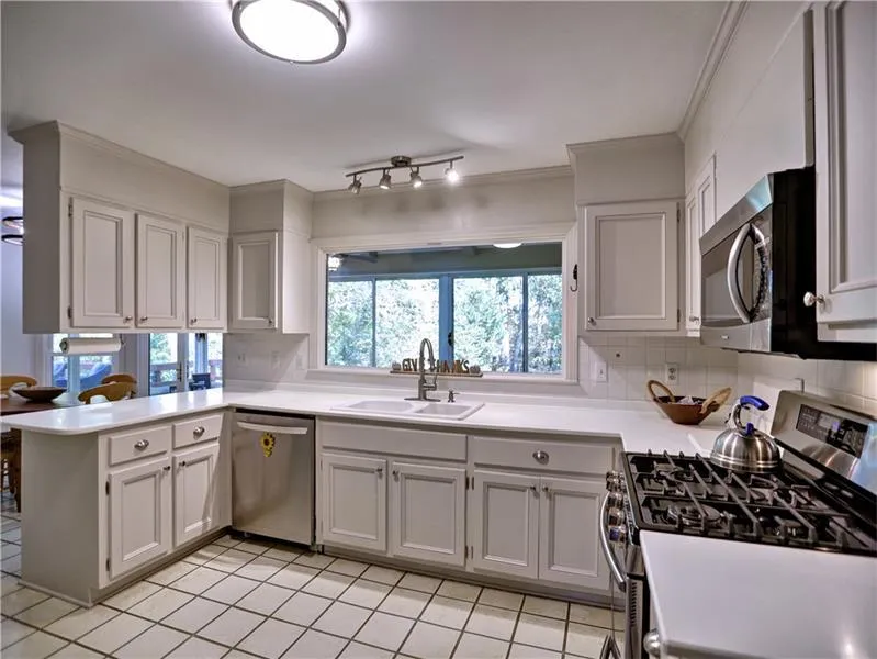Kitchen with kitchen peninsula, stainless steel appliances, white cabinets, and sink