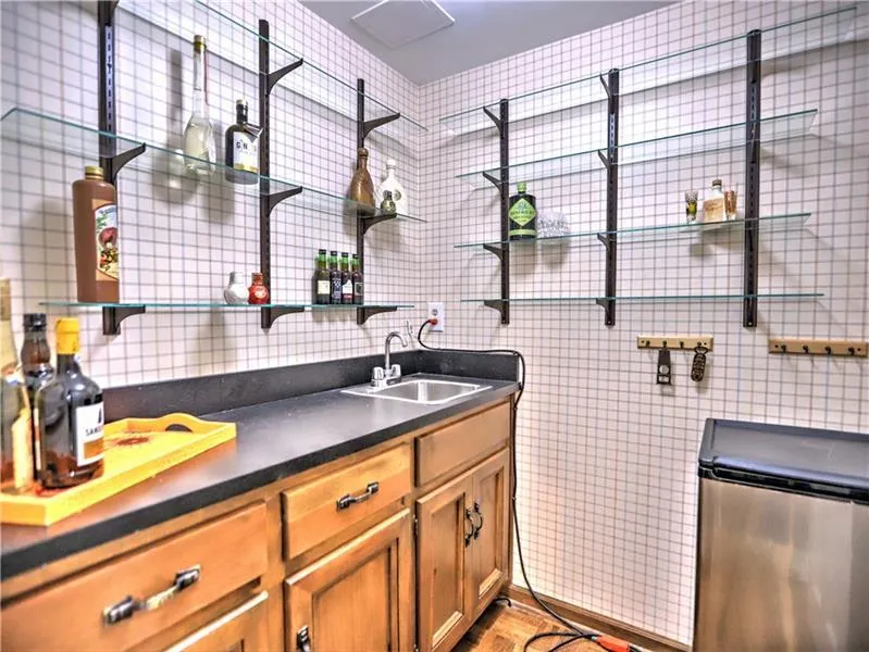 Kitchen with light hardwood / wood-style flooring, stainless steel refrigerator, tile walls, and sink