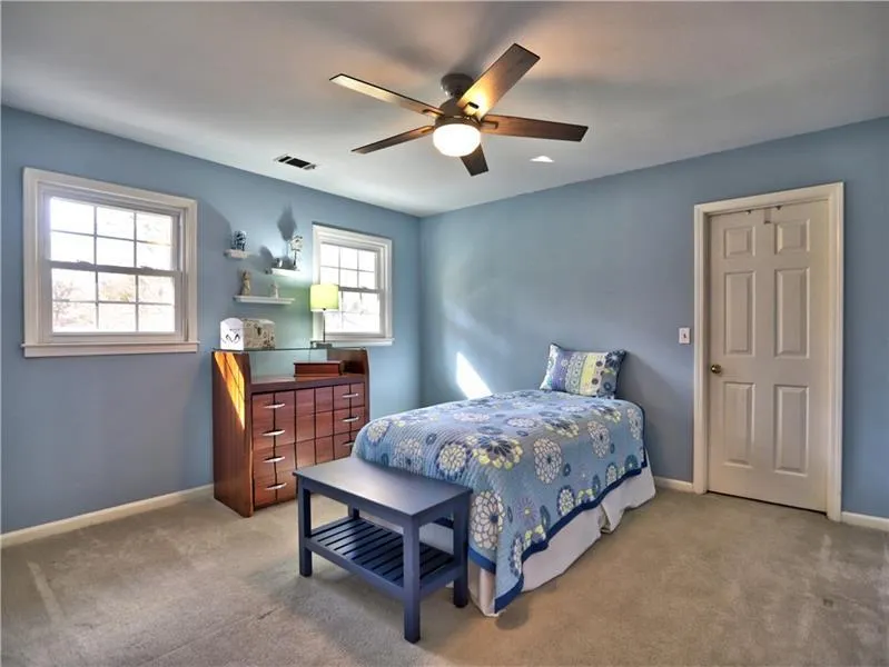 Bedroom featuring ceiling fan, light colored carpet, and multiple windows