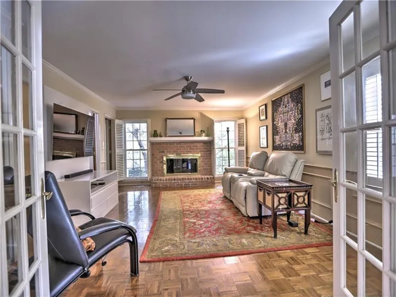 Living room with a wealth of natural light, ceiling fan, ornamental molding, and parquet flooring