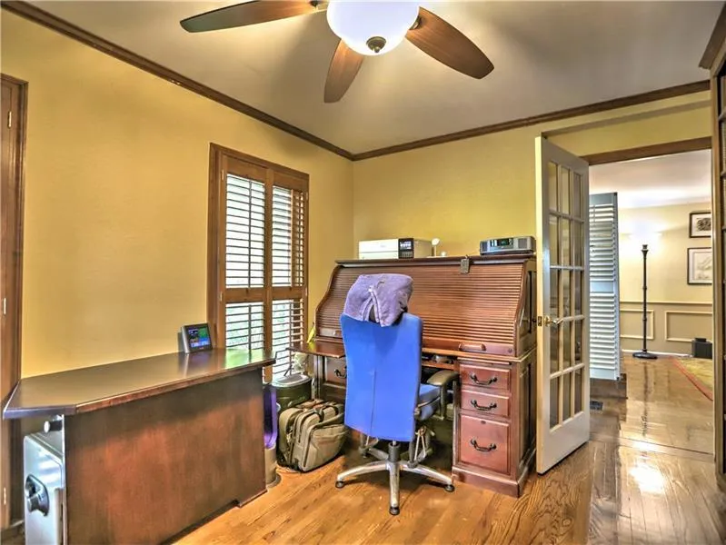 Home office with hardwood / wood-style flooring, ceiling fan, and ornamental molding