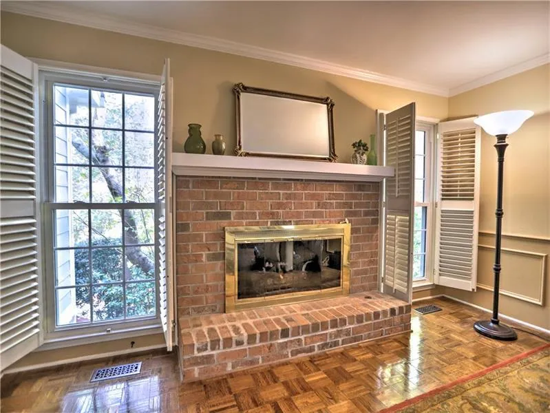 Living room with a brick fireplace, crown molding, and parquet flooring