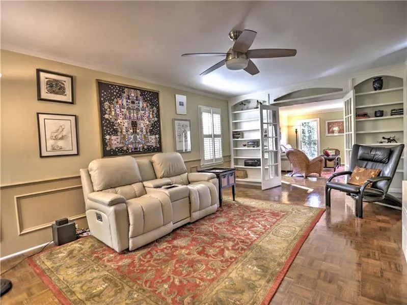 Living room featuring dark parquet flooring, ceiling fan, and ornamental molding