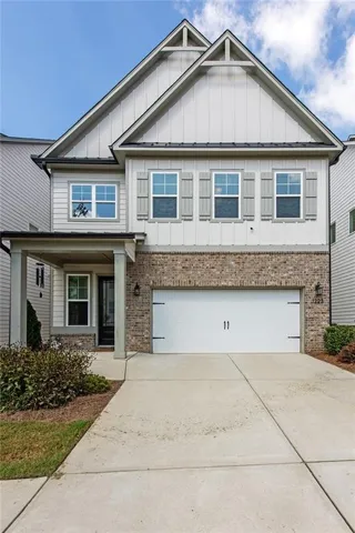 Exterior showcasing brick and siding facade, covered front porch, and an attached two-car garage
