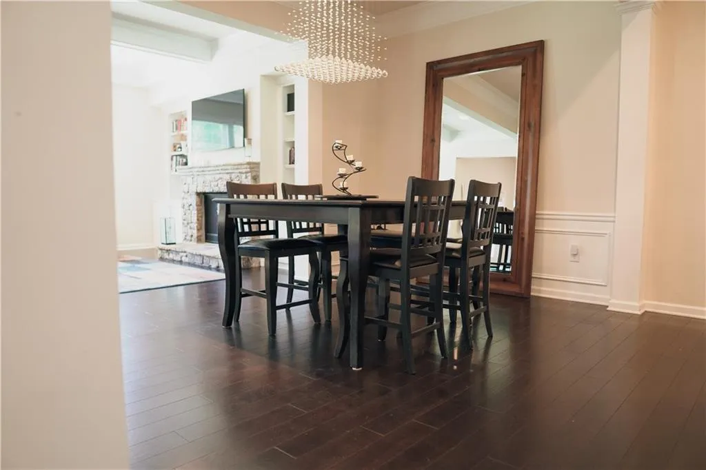 Dining area with ornamental molding, an inviting chandelier, and dark wood-type flooring