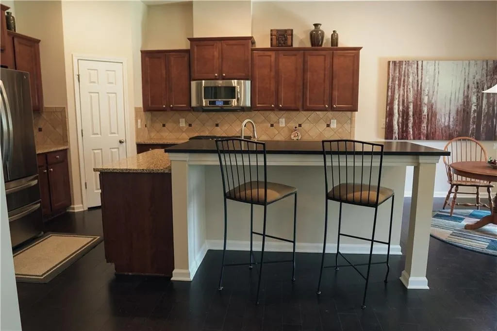 Kitchen with a breakfast bar, dark hardwood / wood-style flooring, tasteful backsplash, and stainless steel appliances