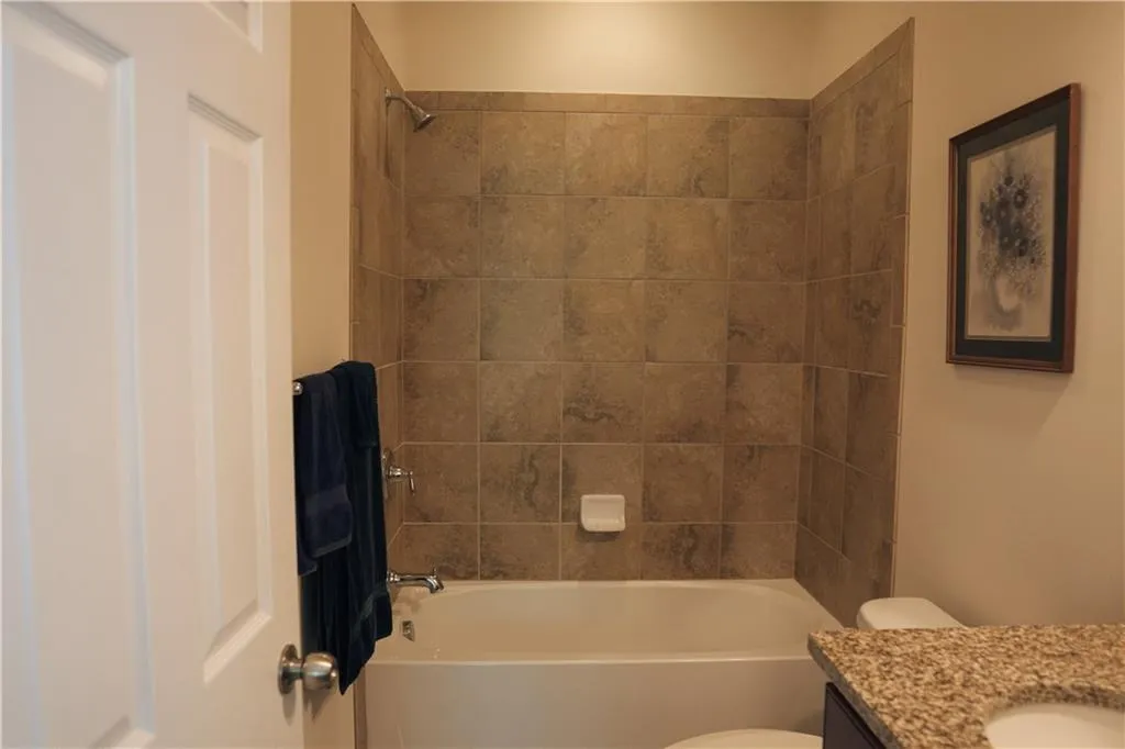 Full bathroom featuring vanity, tiled shower / bath combo, and toilet
