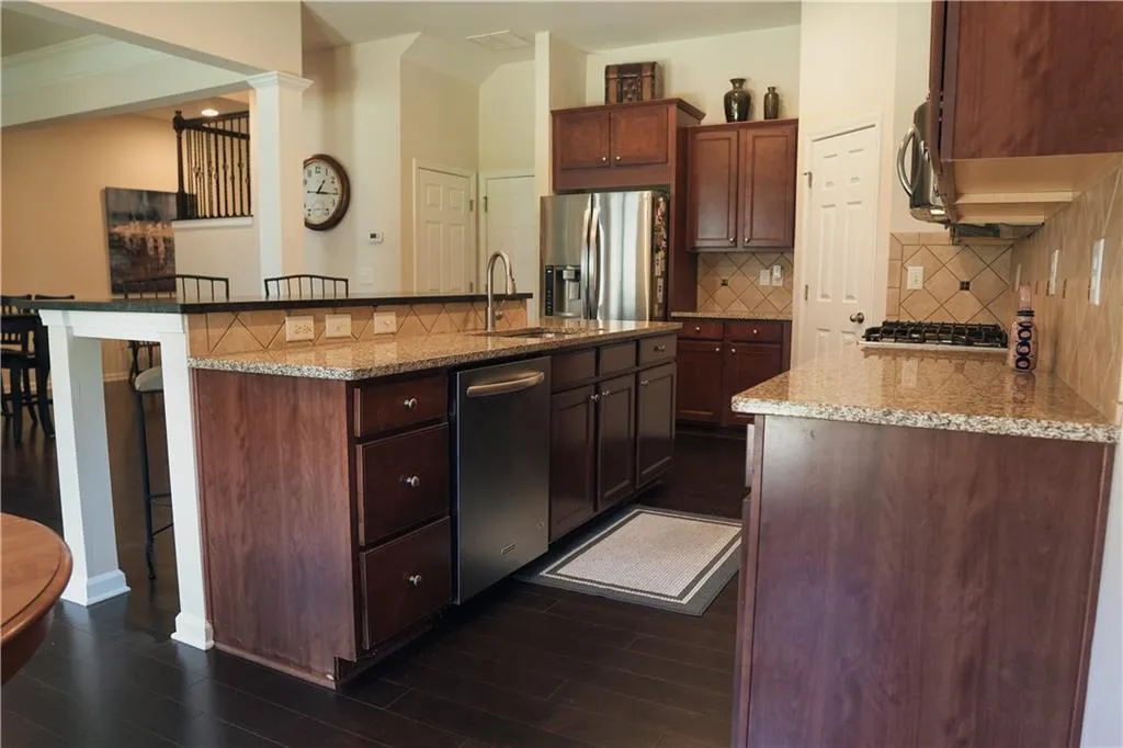 Kitchen featuring sink, a center island with sink, backsplash, and stainless steel appliances