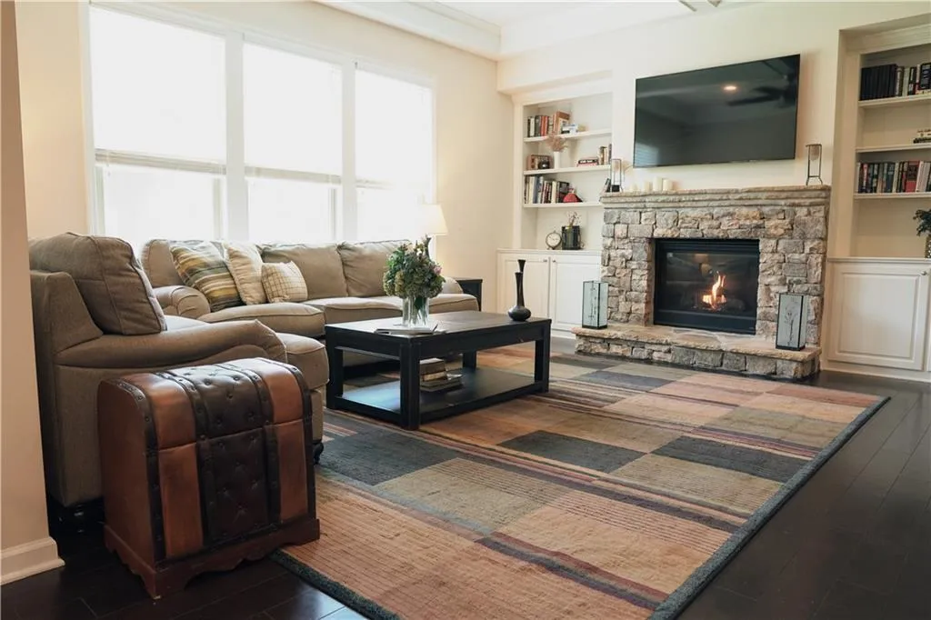 Living room featuring built in shelves, a fireplace, crown molding, and dark hardwood / wood-style floors