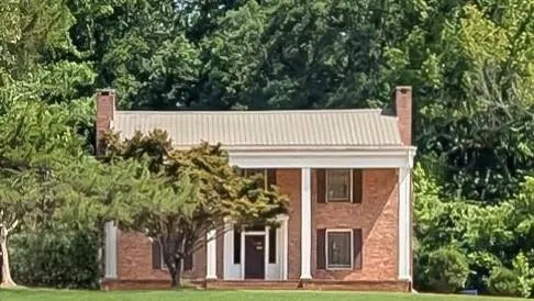 Brick colonial-style residence featuring a metal roof and two prominent brick chimneys