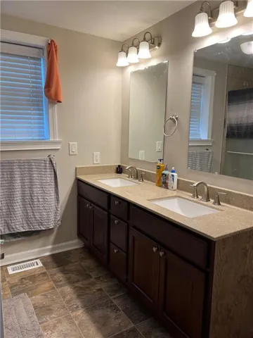 Dual vanity with dark wood-finish cabinetry, light-toned countertops, and undermount sinks