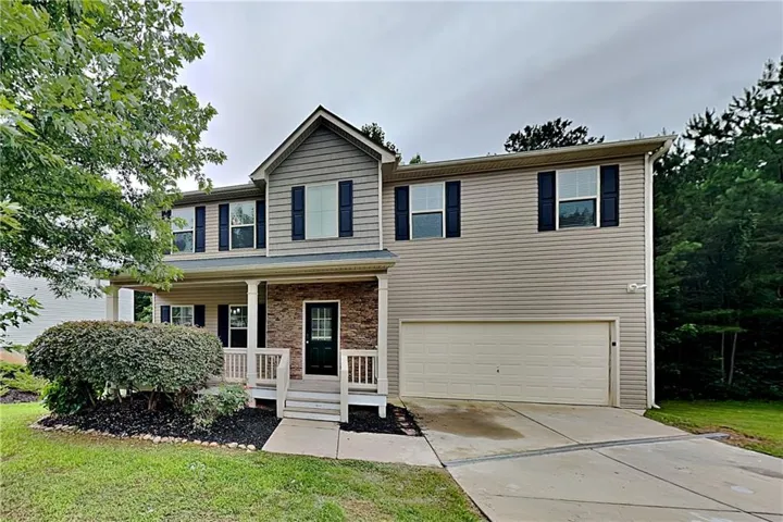 Two-story residence featuring a covered front porch, a two-car garage, and stone accents