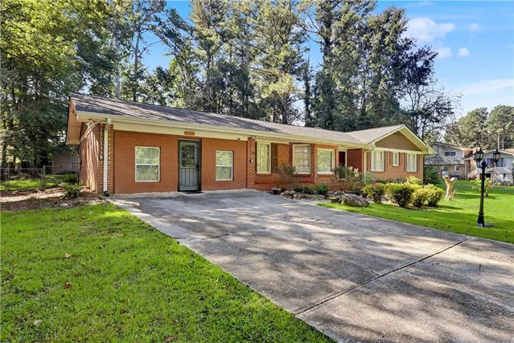 Red brick exterior with white trim, a dark gray front door, and a concrete driveway