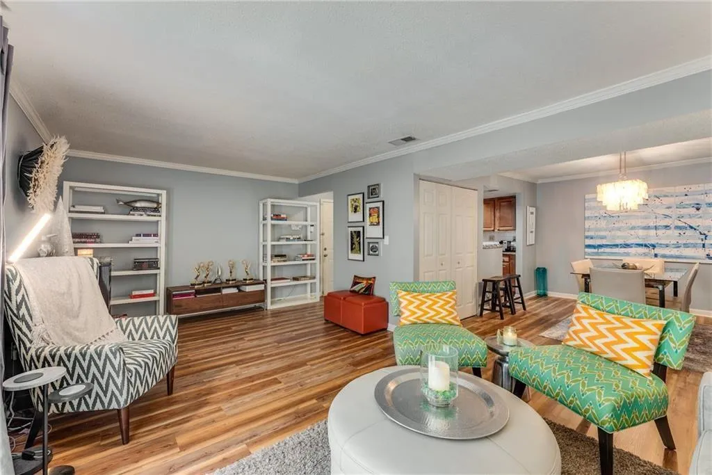 Sitting room with ornamental molding, suspended lighting, and wood finished floors