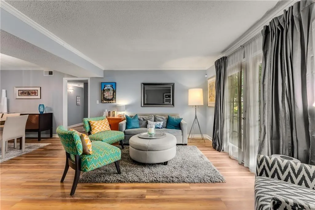 Living room with a textured ceiling, light wood finished floors, and crown molding