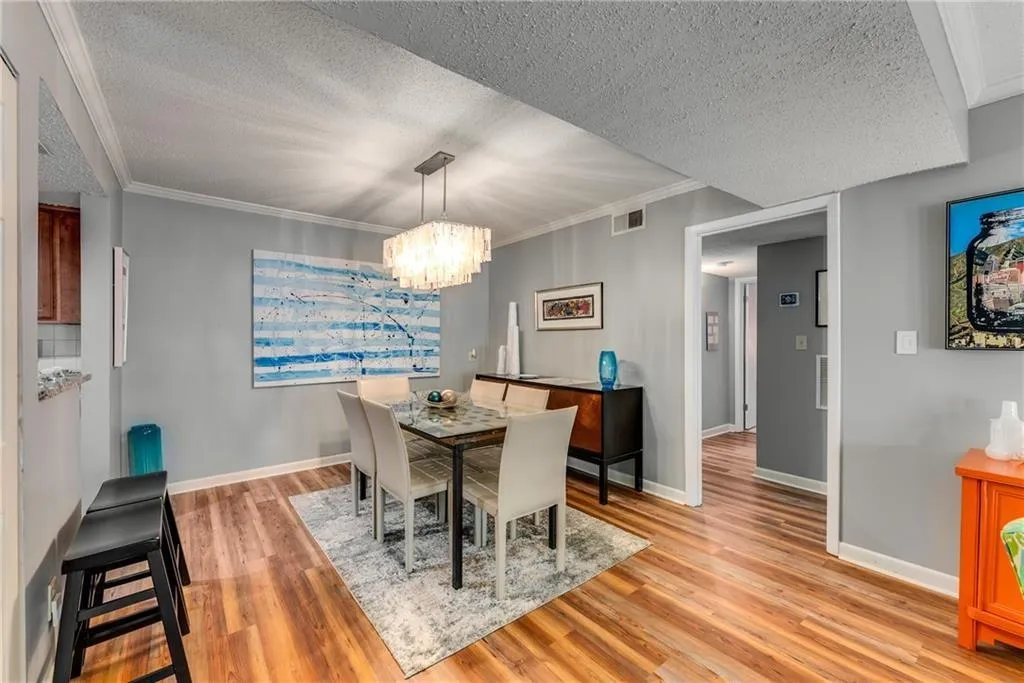 Dining area featuring ornamental molding, light wood finished floors, a textured ceiling, and a chandelier