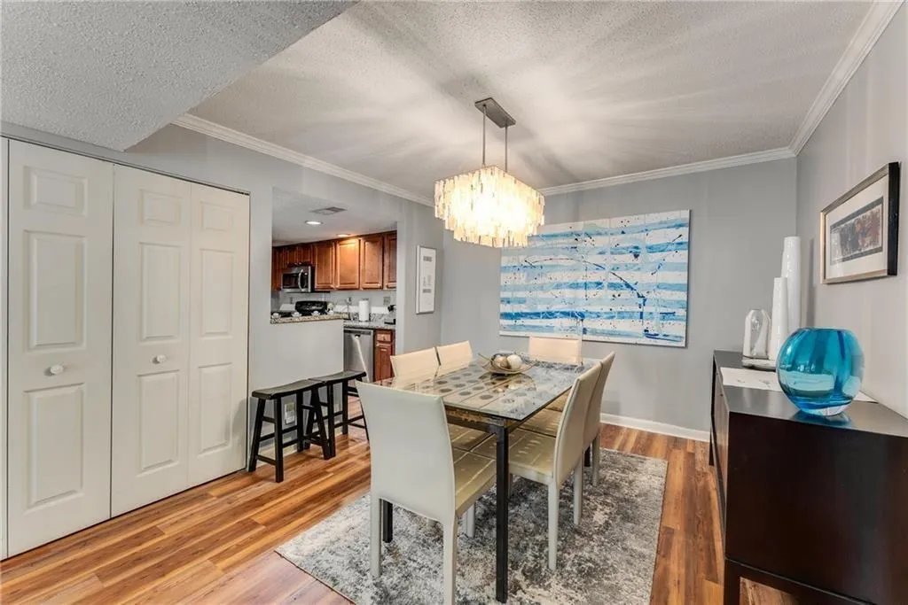 Dining space with light wood-style floors, crown molding, suspended lighting, and a textured ceiling
