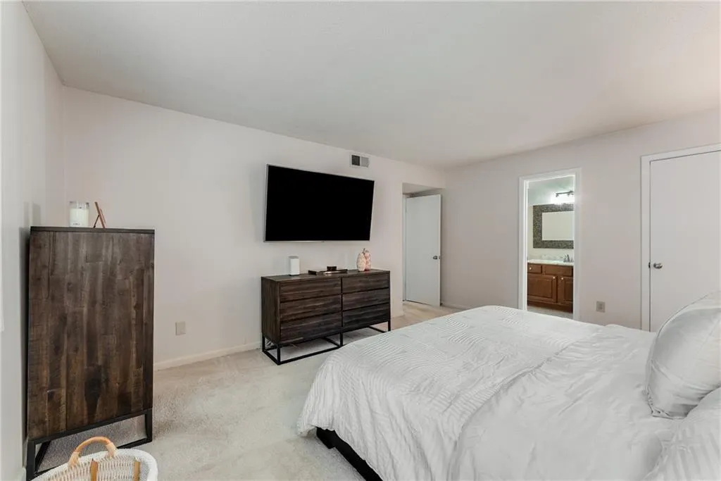 Bedroom with light carpet and connected bathroom
