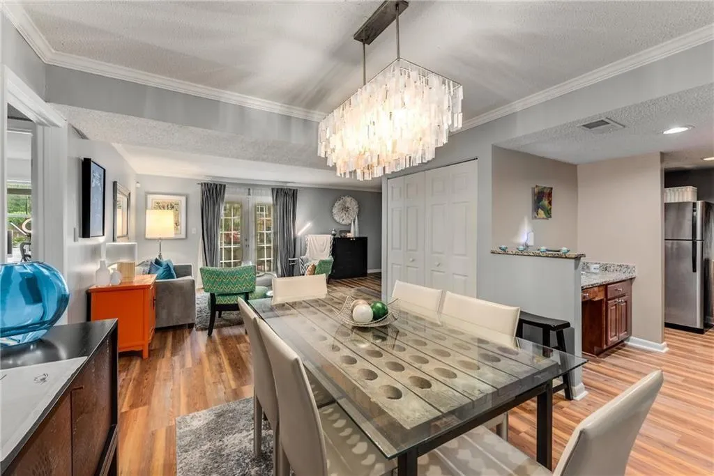 Dining area with a textured ceiling, light wood-type flooring, crown molding, and hanging lights