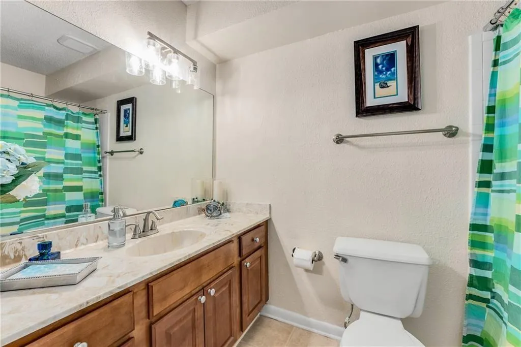 Full bath featuring a shower with curtain, vanity, and a textured wall