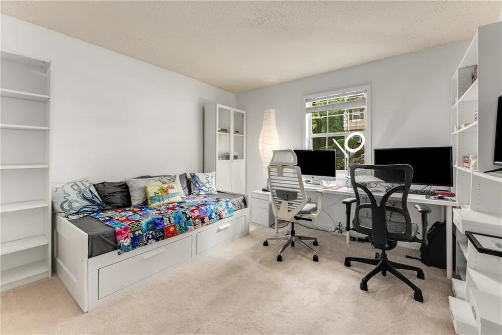 Bedroom featuring a textured ceiling, light colored carpet, and a desk
