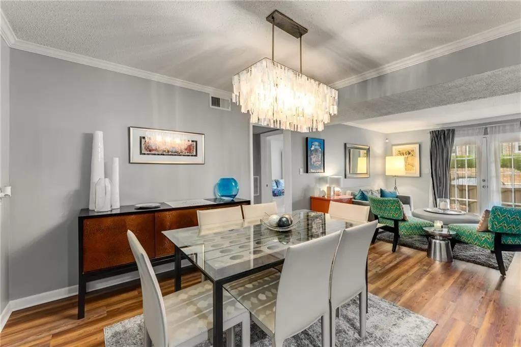 Dining space with french doors, ornamental molding, a textured ceiling, wood finished floors, and hanging lights
