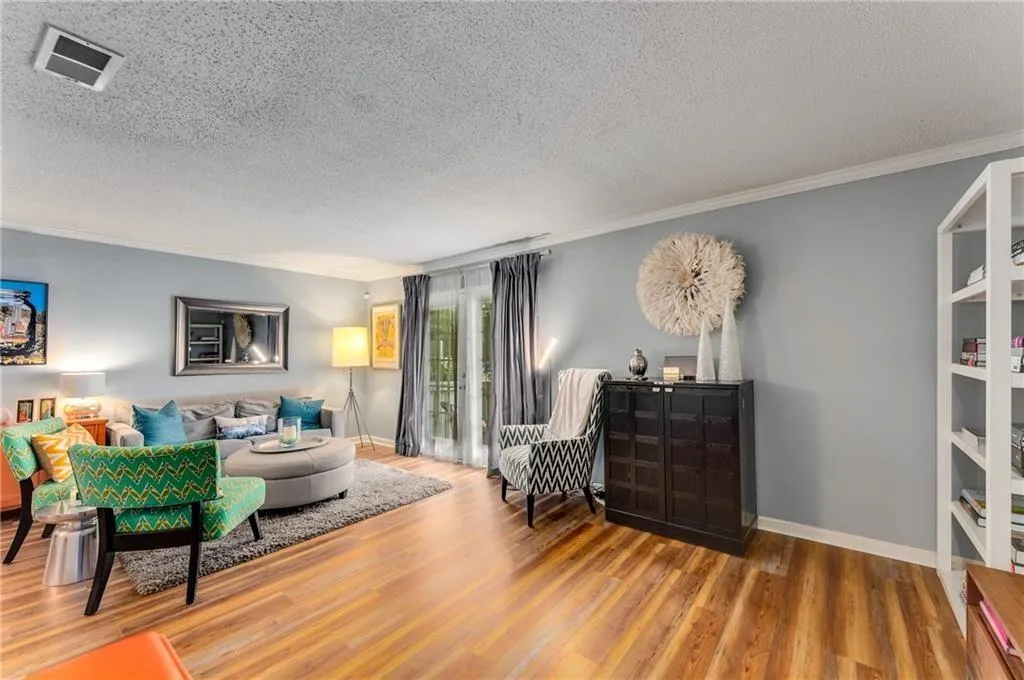 Living area with crown molding, a textured ceiling, and wood finished floors