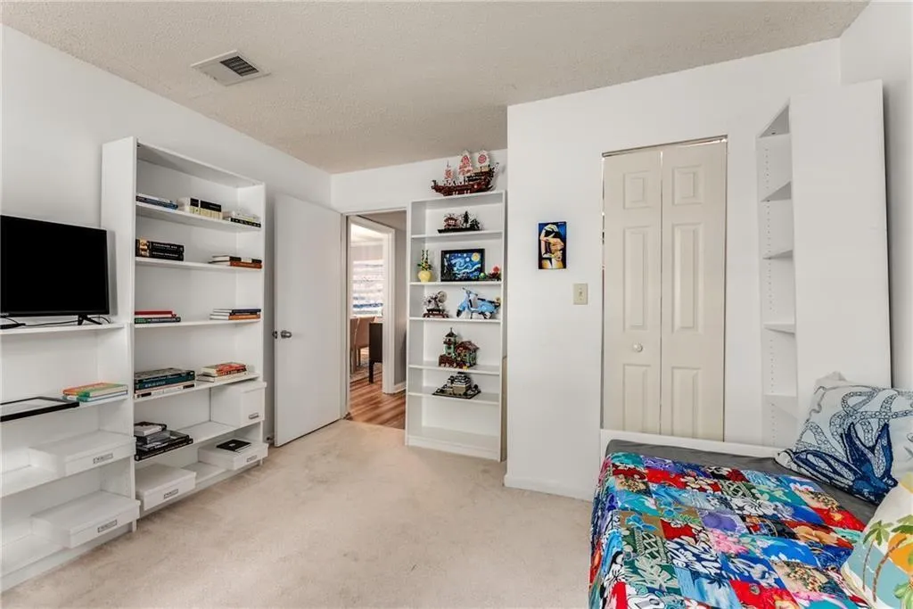 Bedroom with a textured ceiling, light colored carpet, and a closet