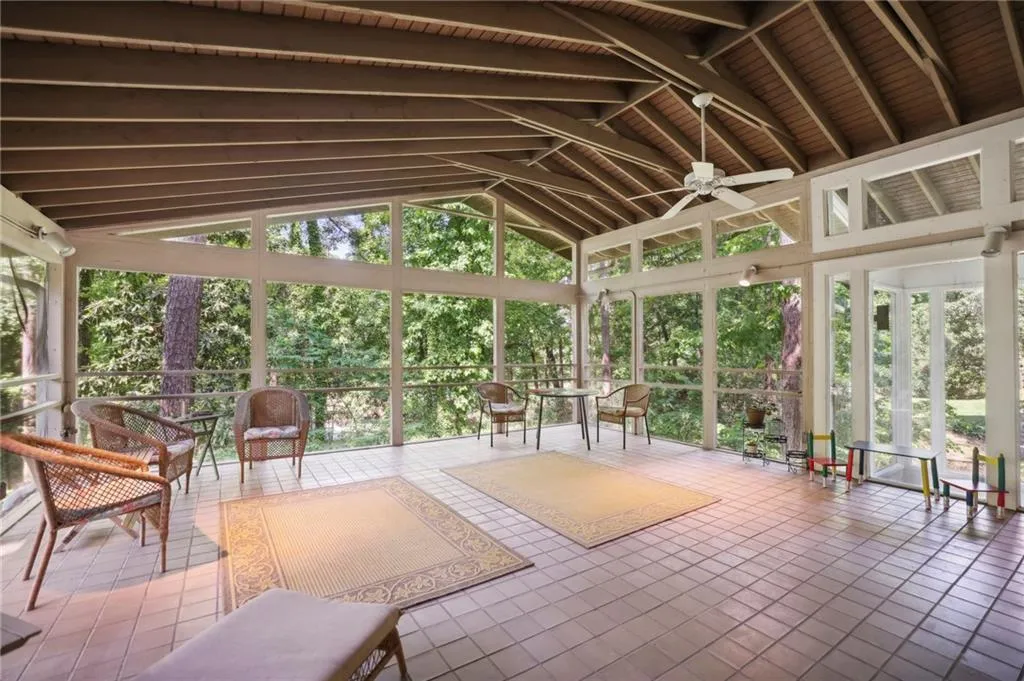 Large sunroom with vaulted ceiling with beams and a healthy amount of sunlight